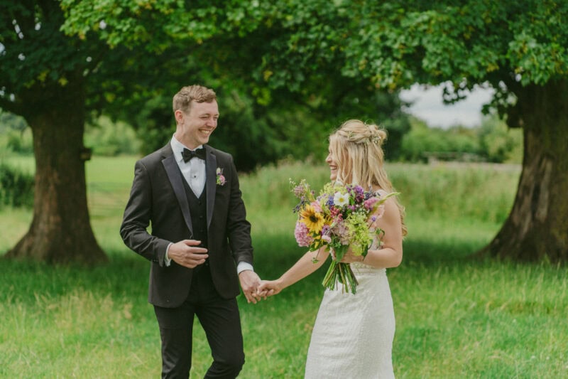 Bride and groom portrait in a field laughing